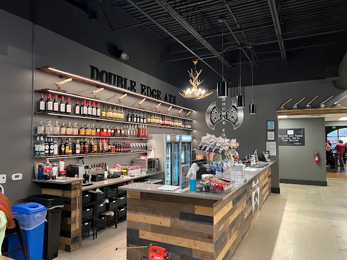 Axe throwing bar counter with a full liquor wall, snacks, and drink coolers