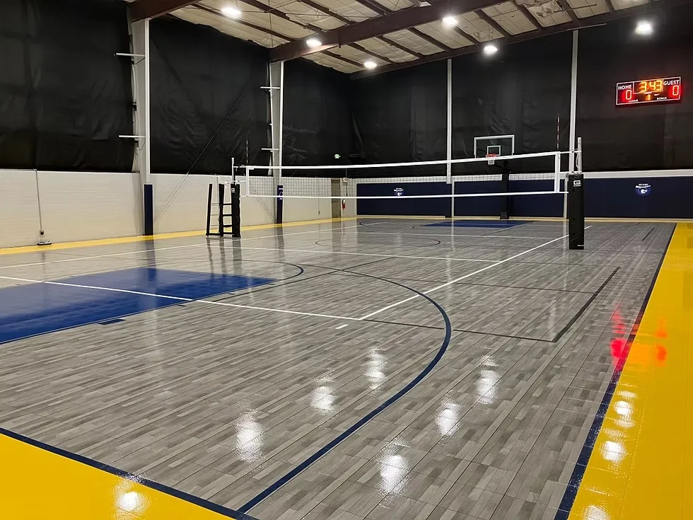 Indoor court set up for volleyball and basketball with a scoreboard